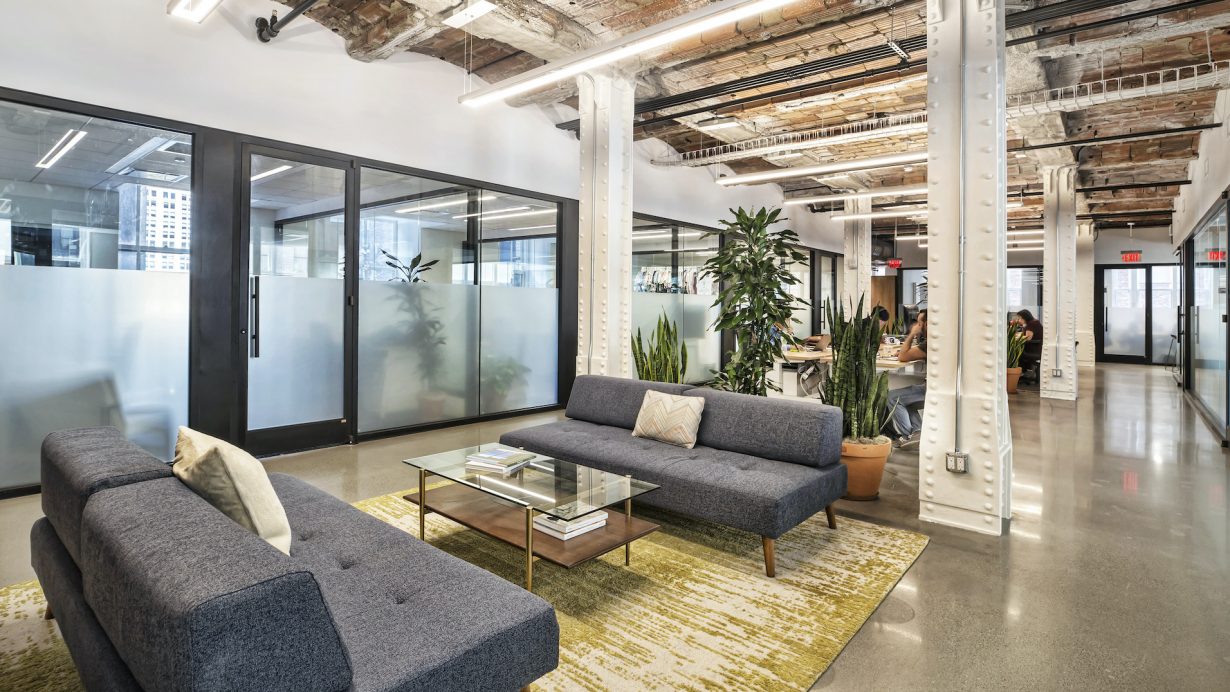 The workplace has an industrial look with high ceilings and exposed ductwork.