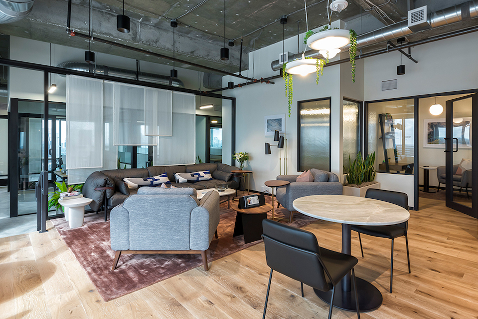 The workplace features industrial touches, such as exposed ductwork and tall, loft-style spaces.