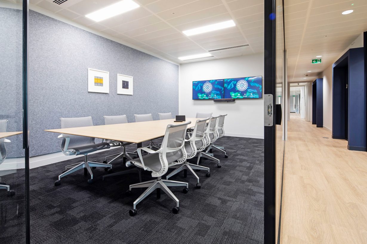 This conference room room has two screens for presentations and hybrid meetings.