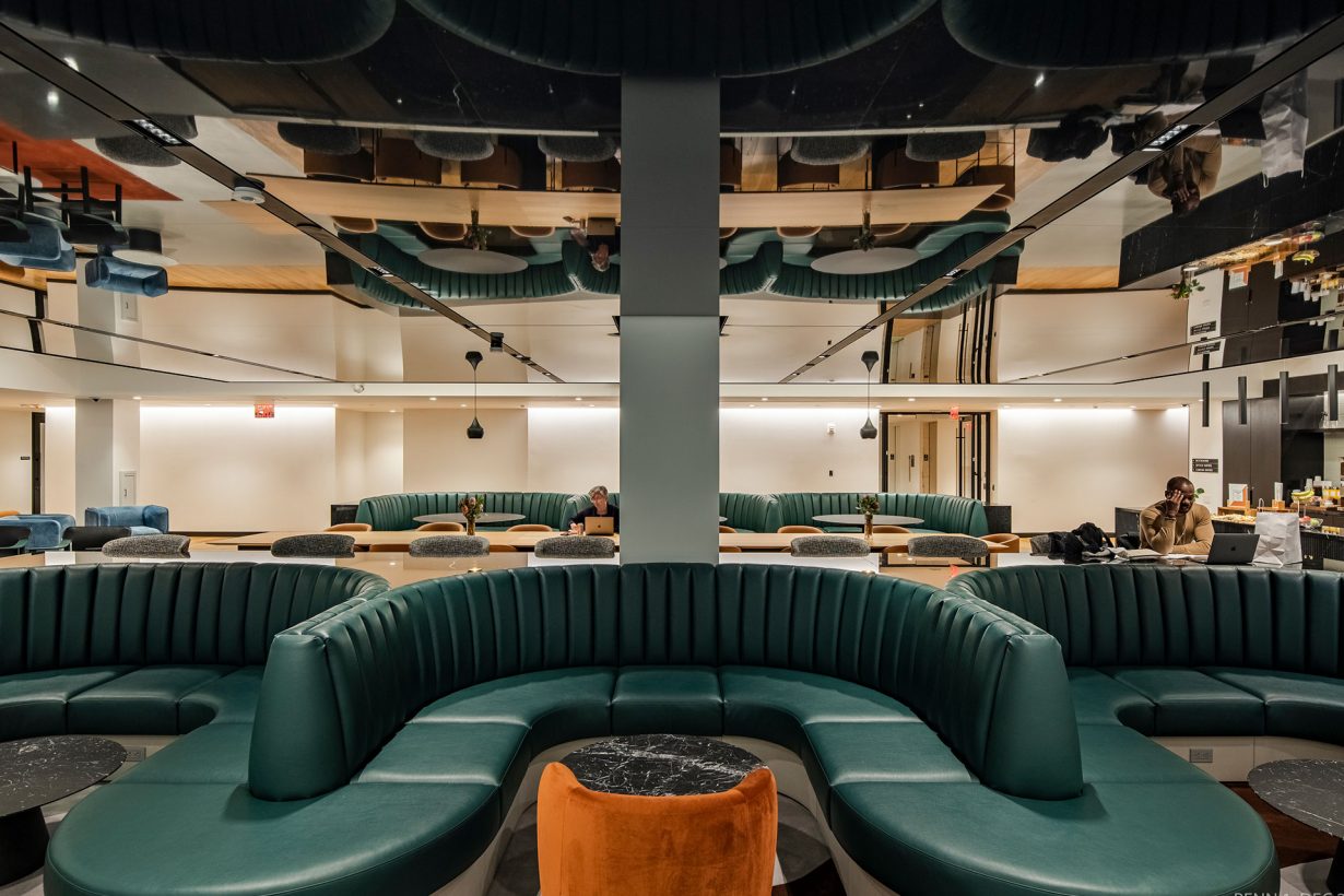 A WorkLife Office Suites by Industrious common area with three U-shaped green leather couches.