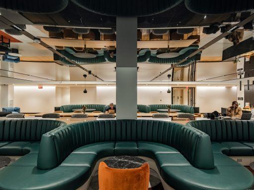 A WorkLife Office Suites by Industrious common area with three U-shaped green leather couches.