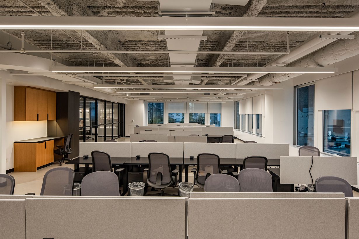 A WorkLife Office Suites working area featuring multiple rows of black desks with grey dividers for visual privacy and grey mesh-back desk chairs.