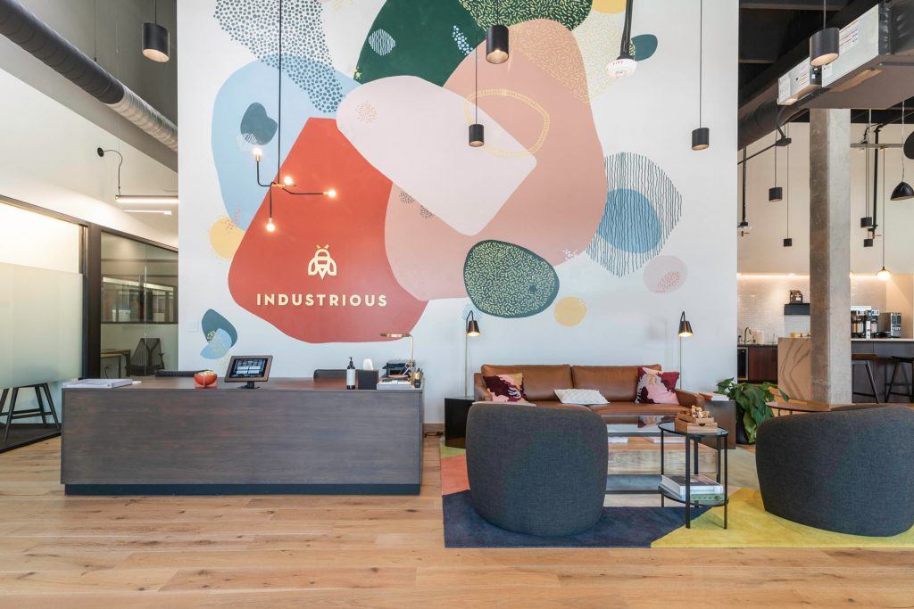 The lobby of Industrious Charlotte NoDa, featuring a colorful mural designed by local artist Mike Wirth.